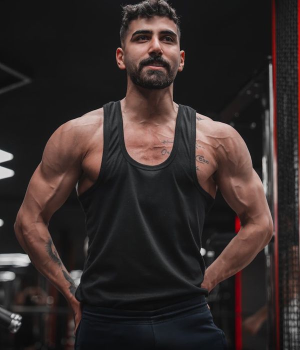 A man in athletic wear performing a controlled strength exercise in a modern, dark gym.
